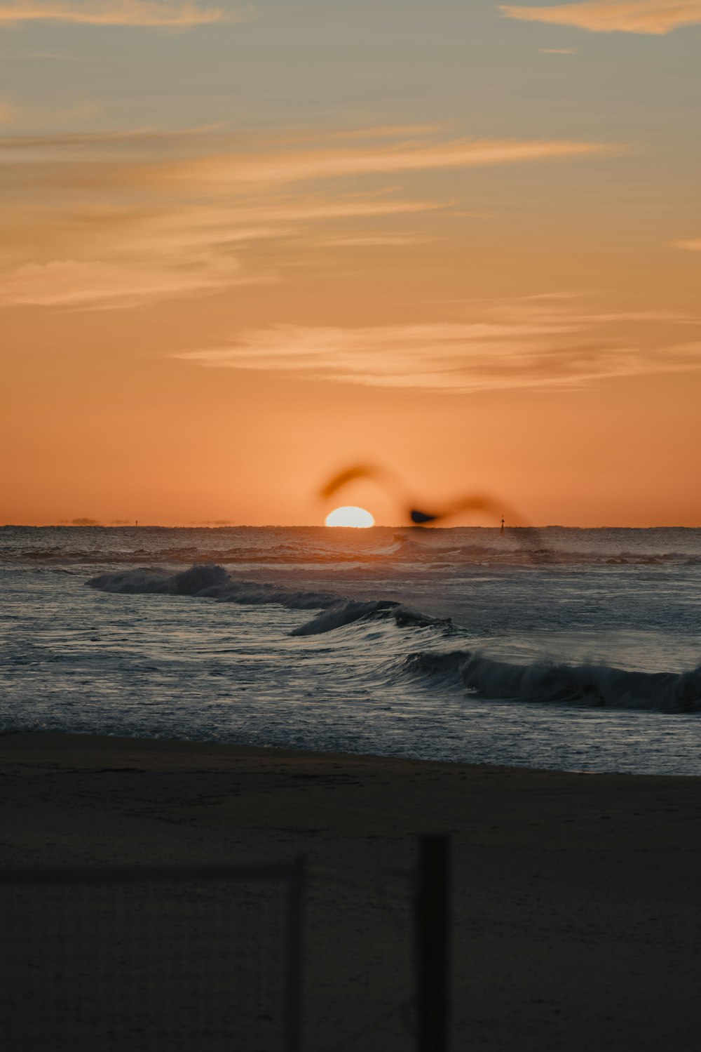 the sun is setting over the ocean with waves