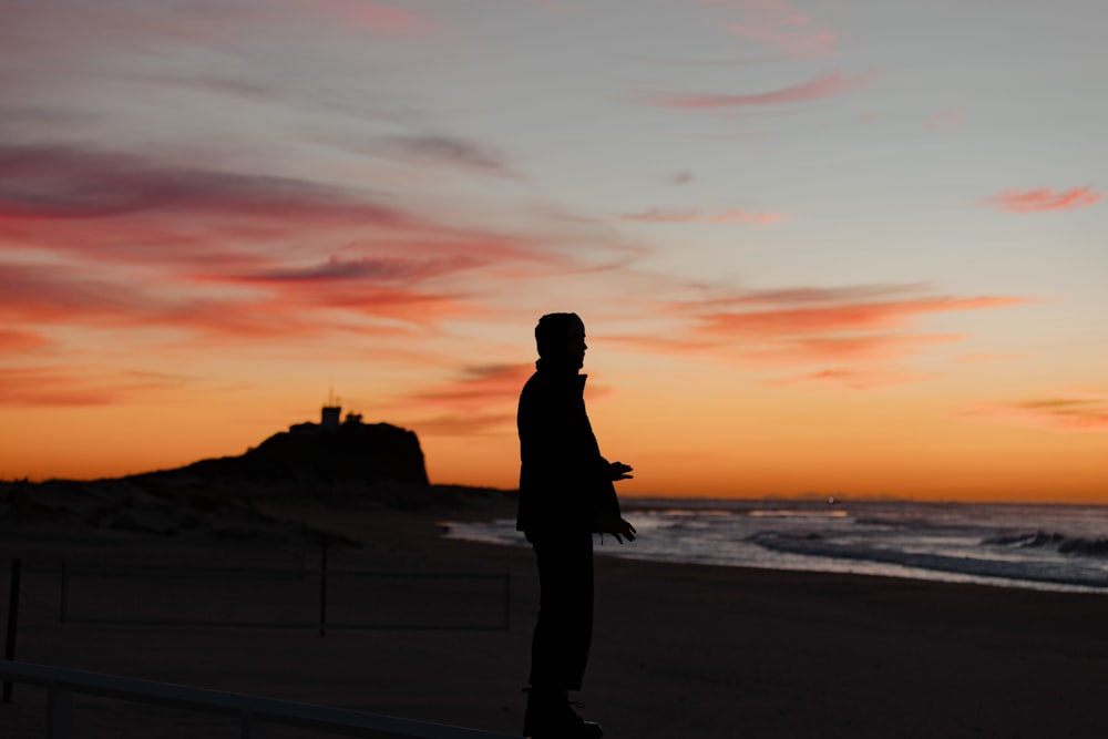 a person standing on a beach at sunset