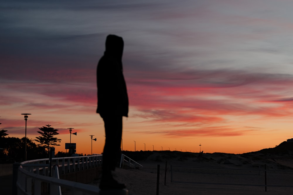 a silhouette of a person standing in front of a sunset