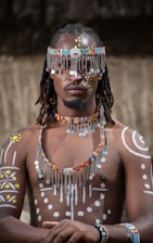 a man wearing a beaded headdress and beads