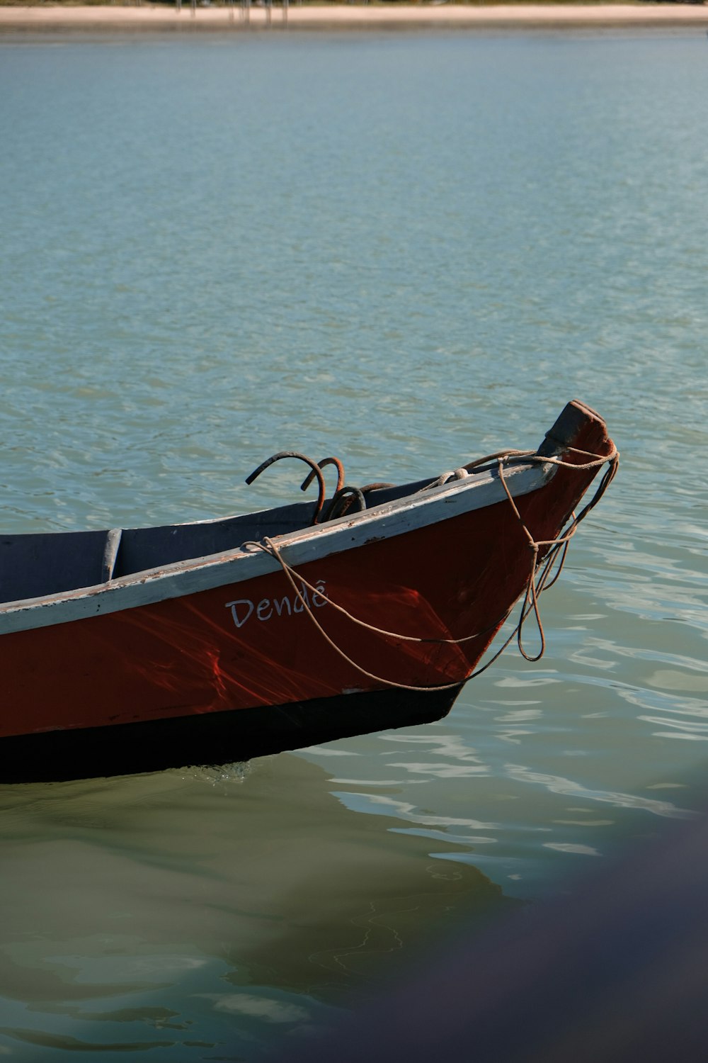 a red and black boat floating on top of a body of water