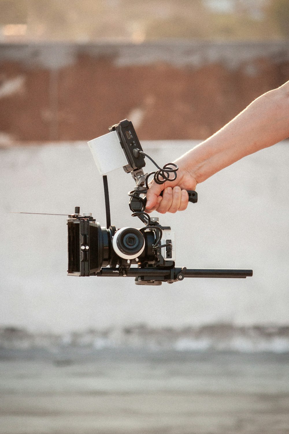 a hand holding a camera attached to a tripod