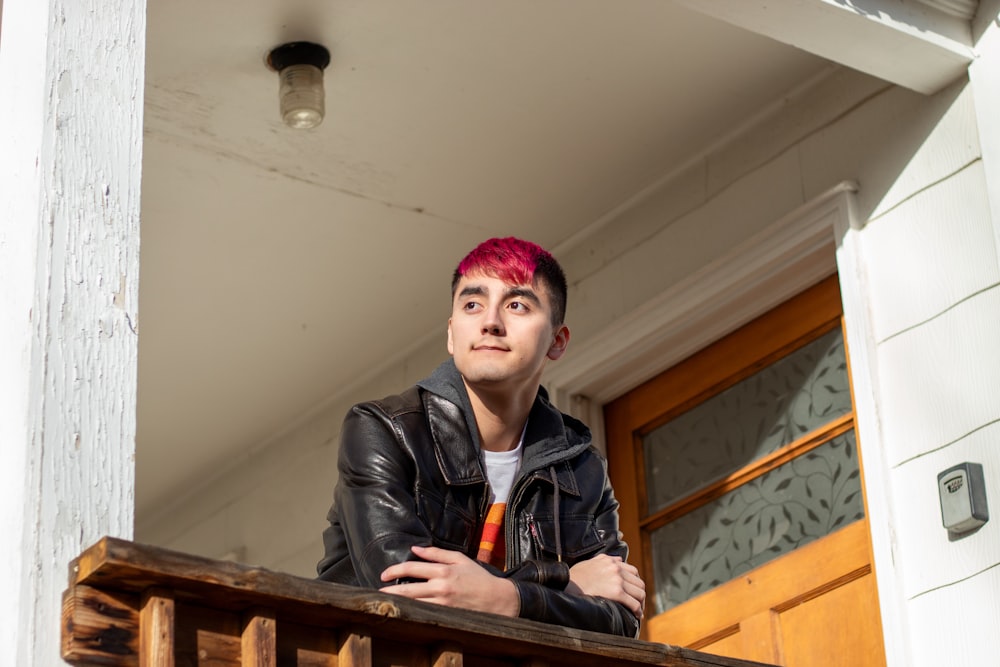 a man with pink hair standing on a porch