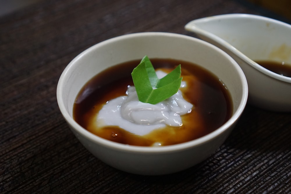 a bowl of soup with a green leaf on top