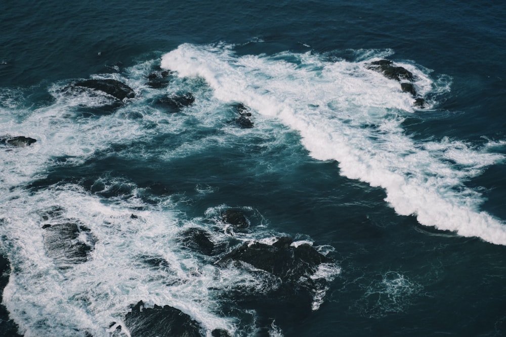 an aerial view of a body of water with rocks