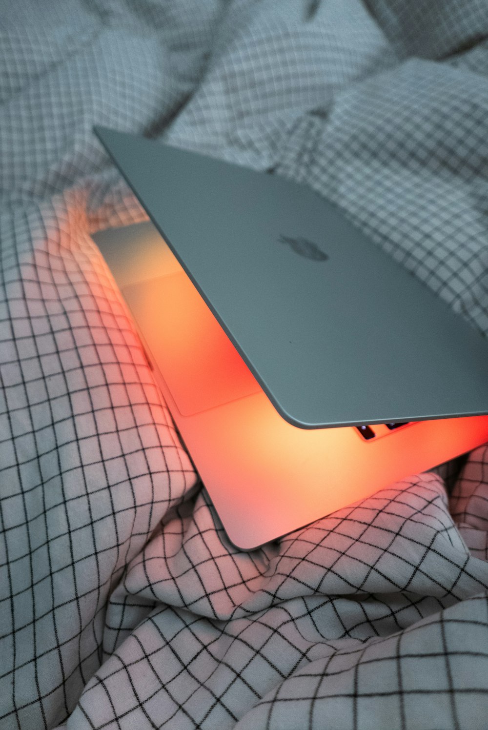 an apple laptop sitting on top of a bed