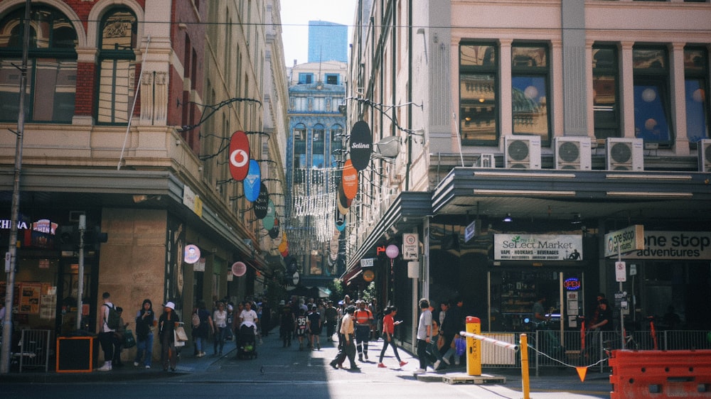 a group of people walking down a street next to tall buildings