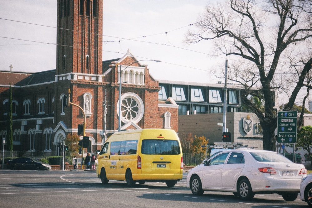 a yellow van driving down a street next to a tall building