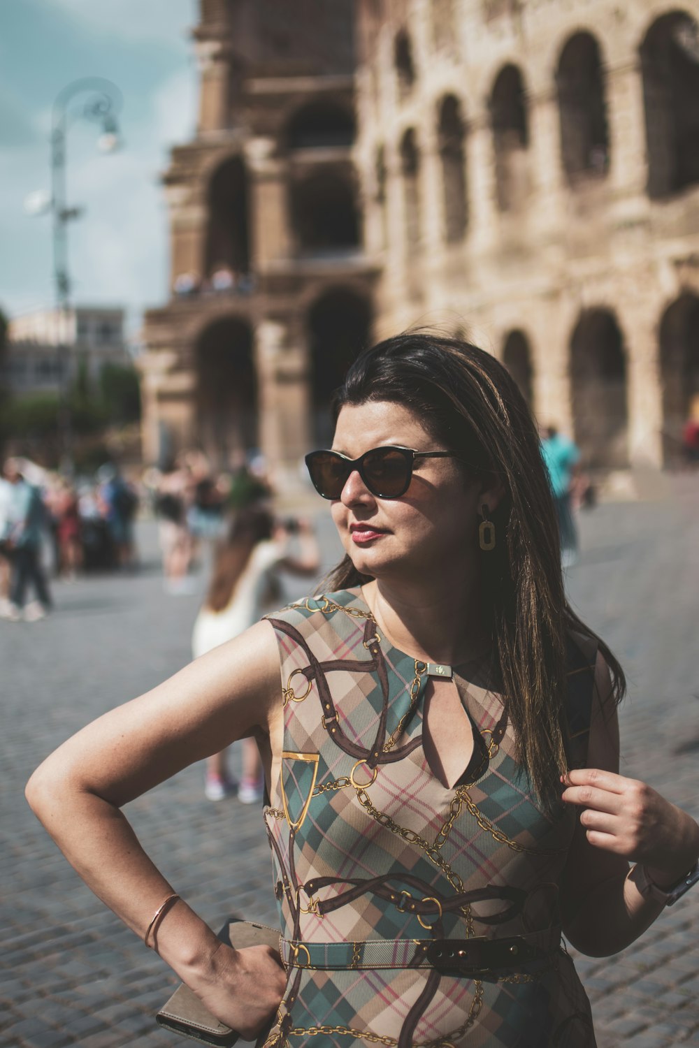 uma mulher de vestido e óculos escuros em frente a um prédio