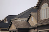 a row of houses with brown shingles and white windows