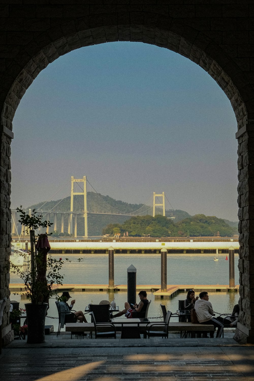 a group of people sitting on benches under a bridge