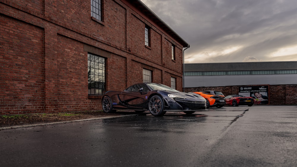 a row of sports cars parked in front of a brick building