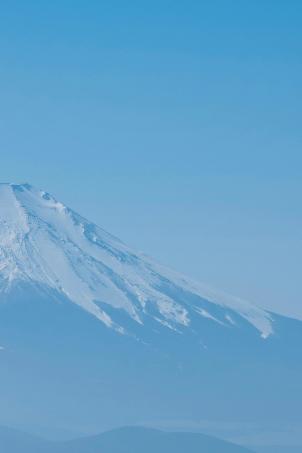 a snow covered mountain in the distance under a blue sky