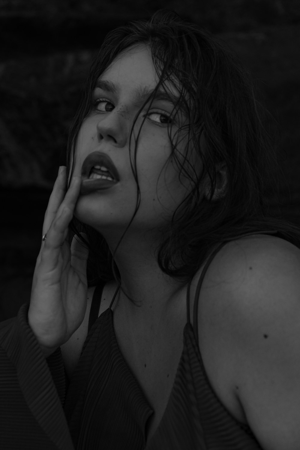 a black and white photo of a woman holding her hand to her face