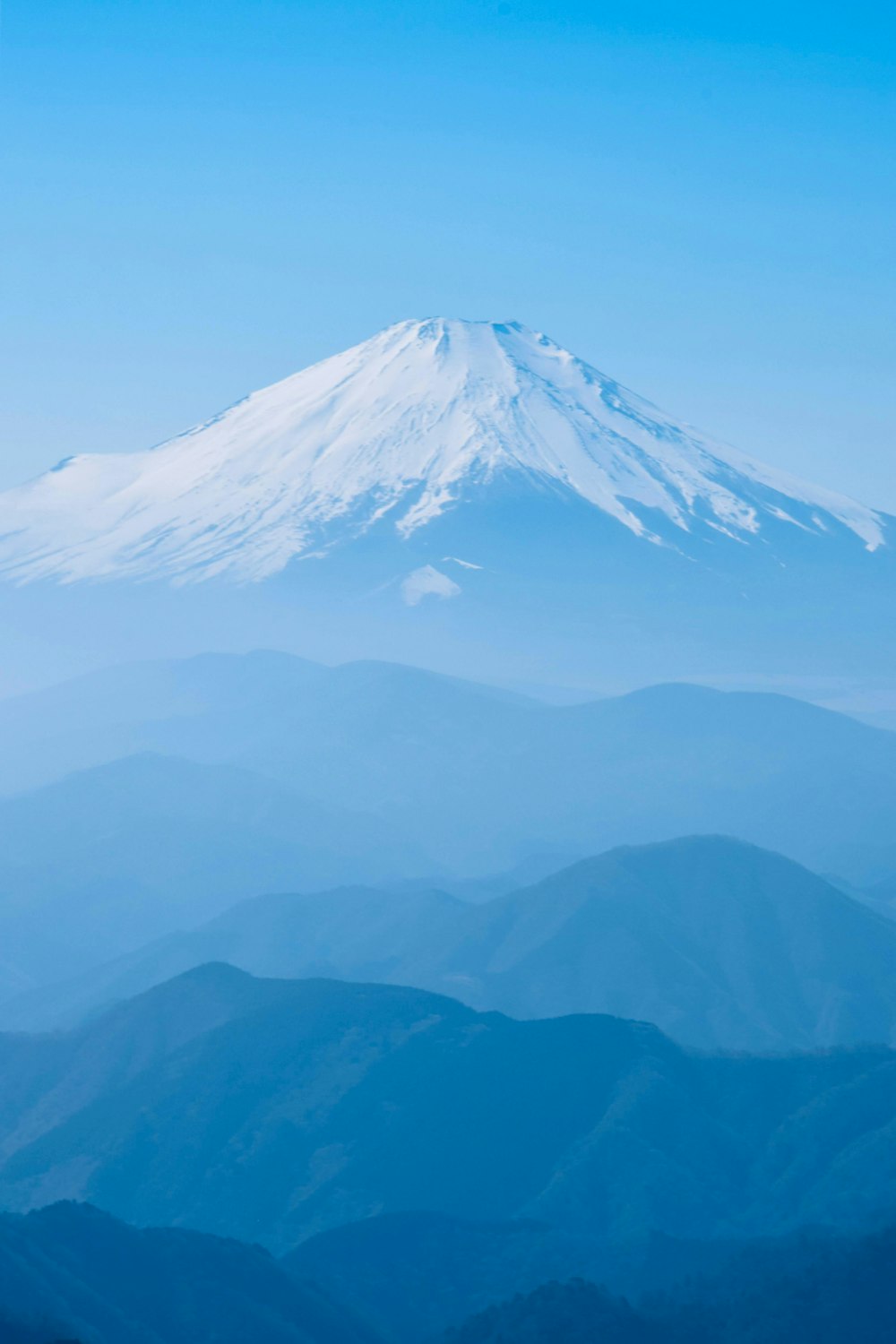 a snow covered mountain in the middle of a blue sky