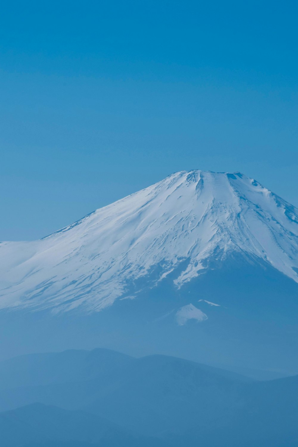 a snow covered mountain in the middle of a blue sky