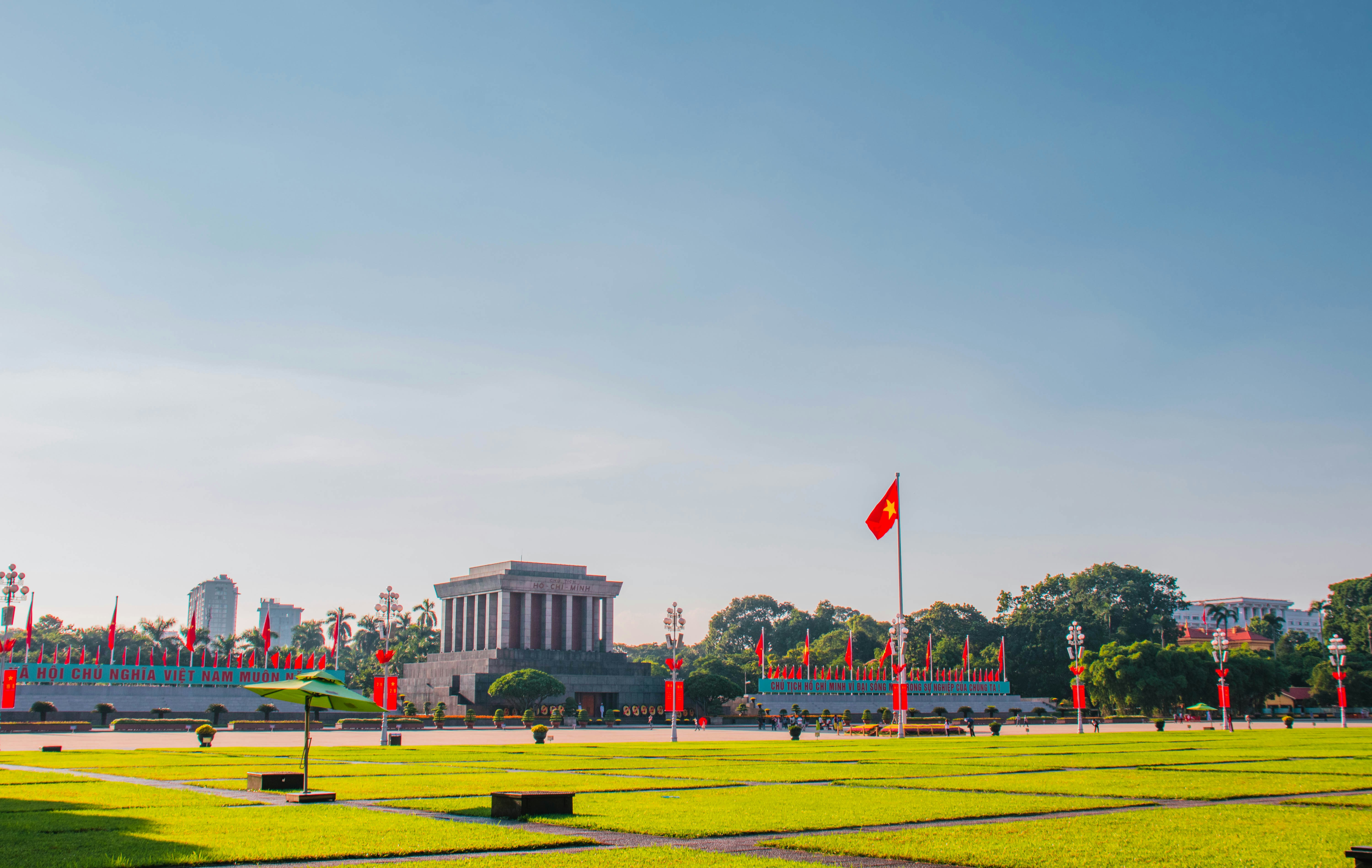 a large grassy field with a building in the background, Ho Chi Minh Mausoleum
