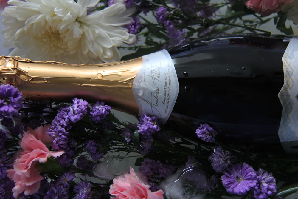 a close up of a bottle of wine with flowers in the background