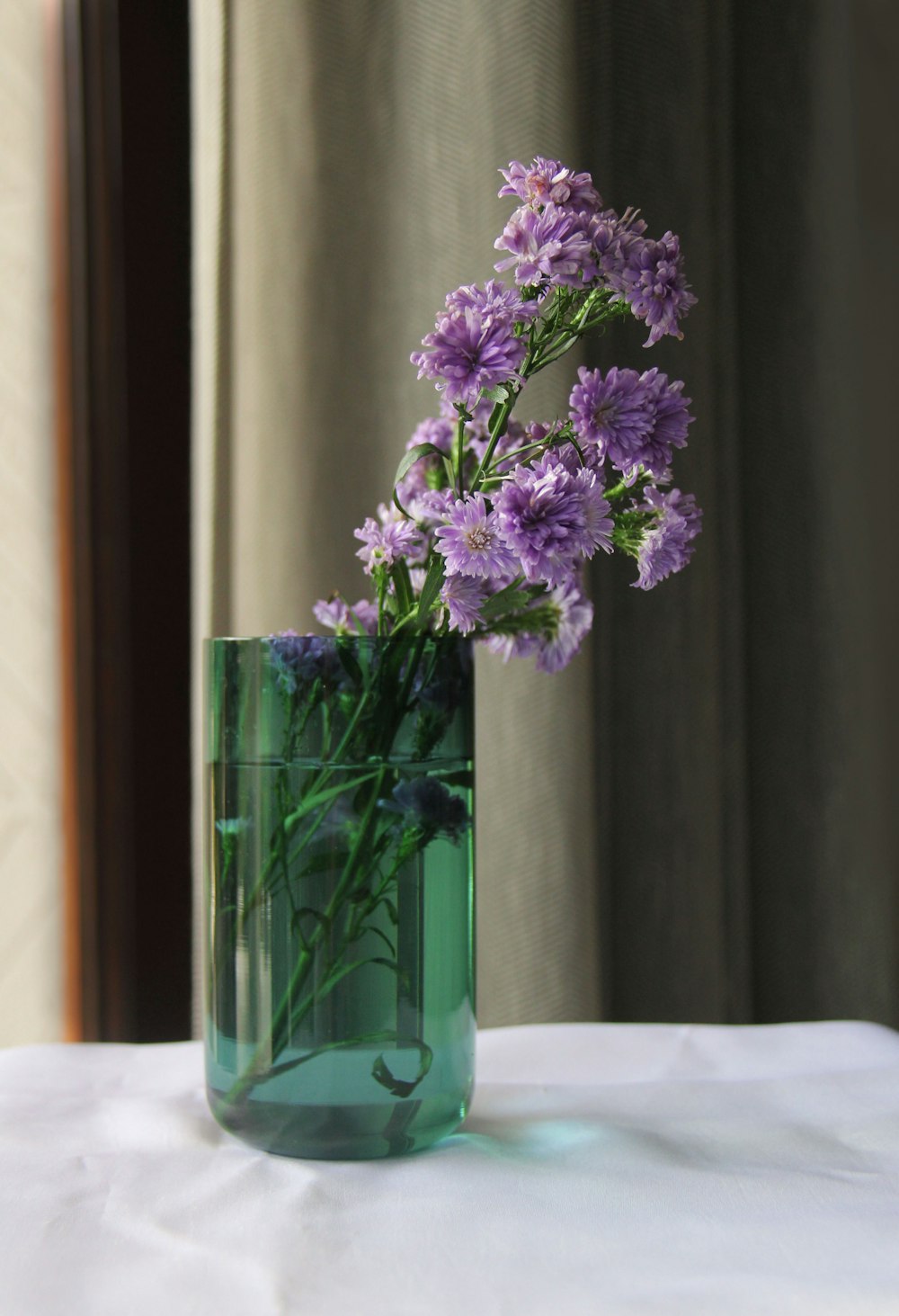 a green vase with purple flowers in it