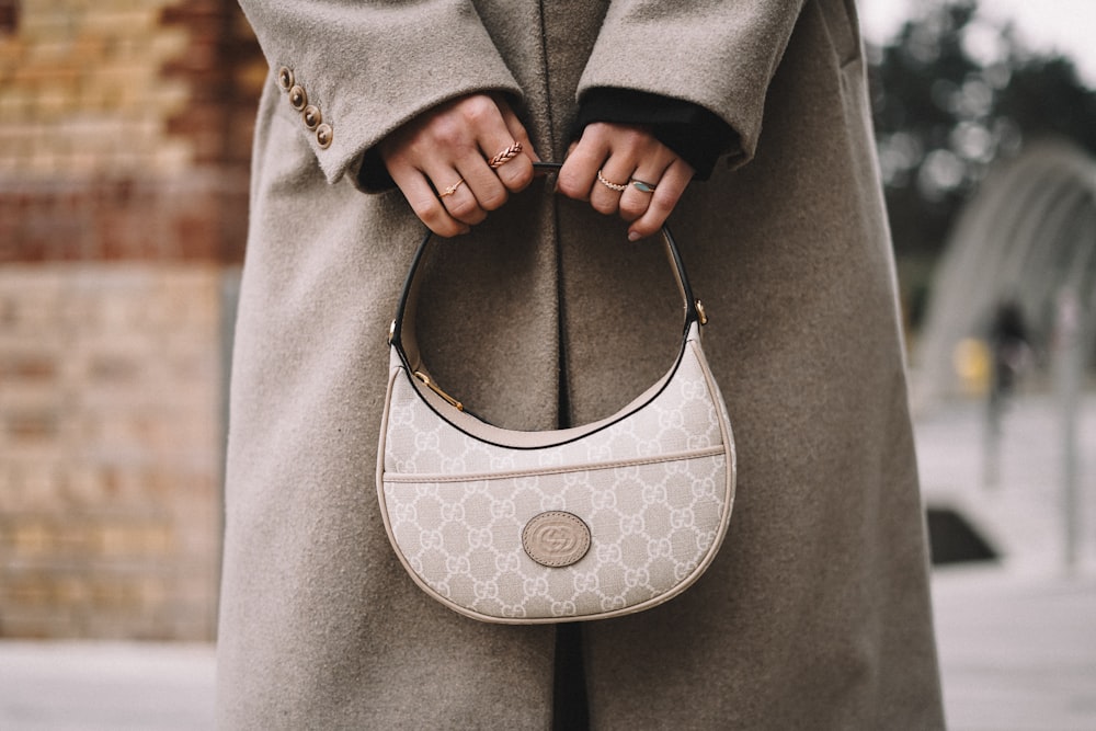 a woman in a coat holding a white purse