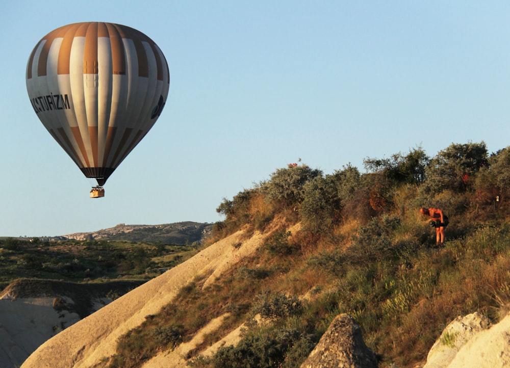 a couple of hot air balloons flying over a hill