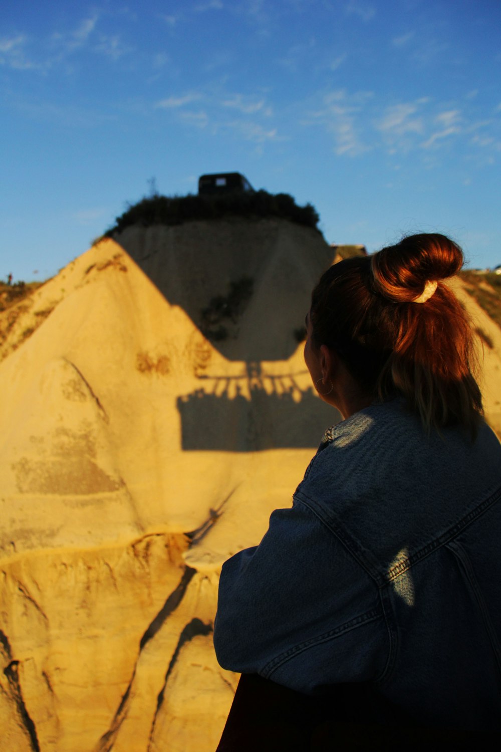 a woman is looking at a hill with a bulldozer in the background