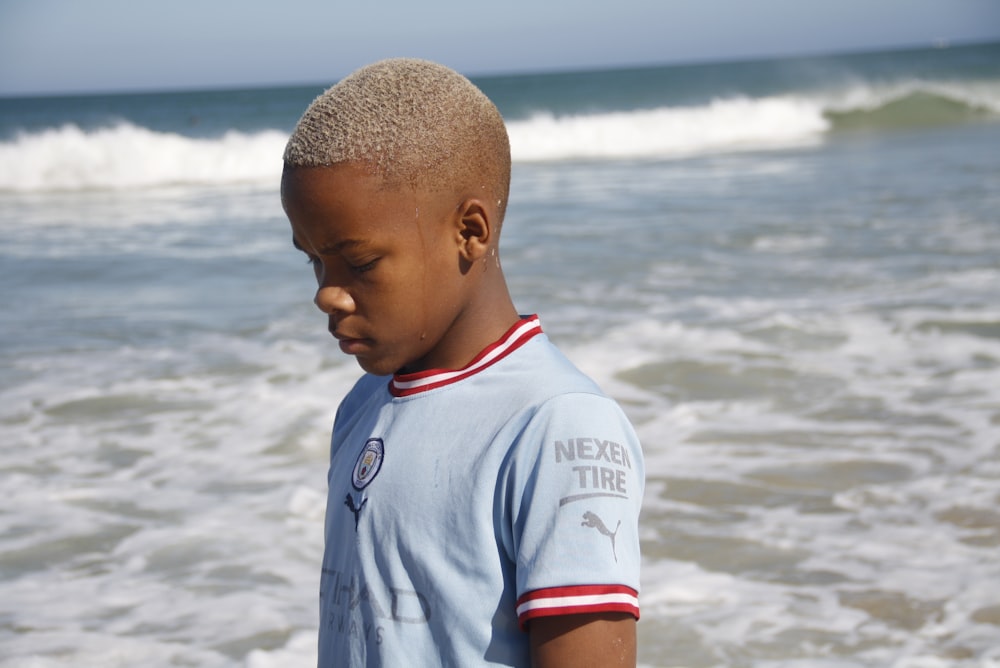 a young boy standing on top of a beach next to the ocean