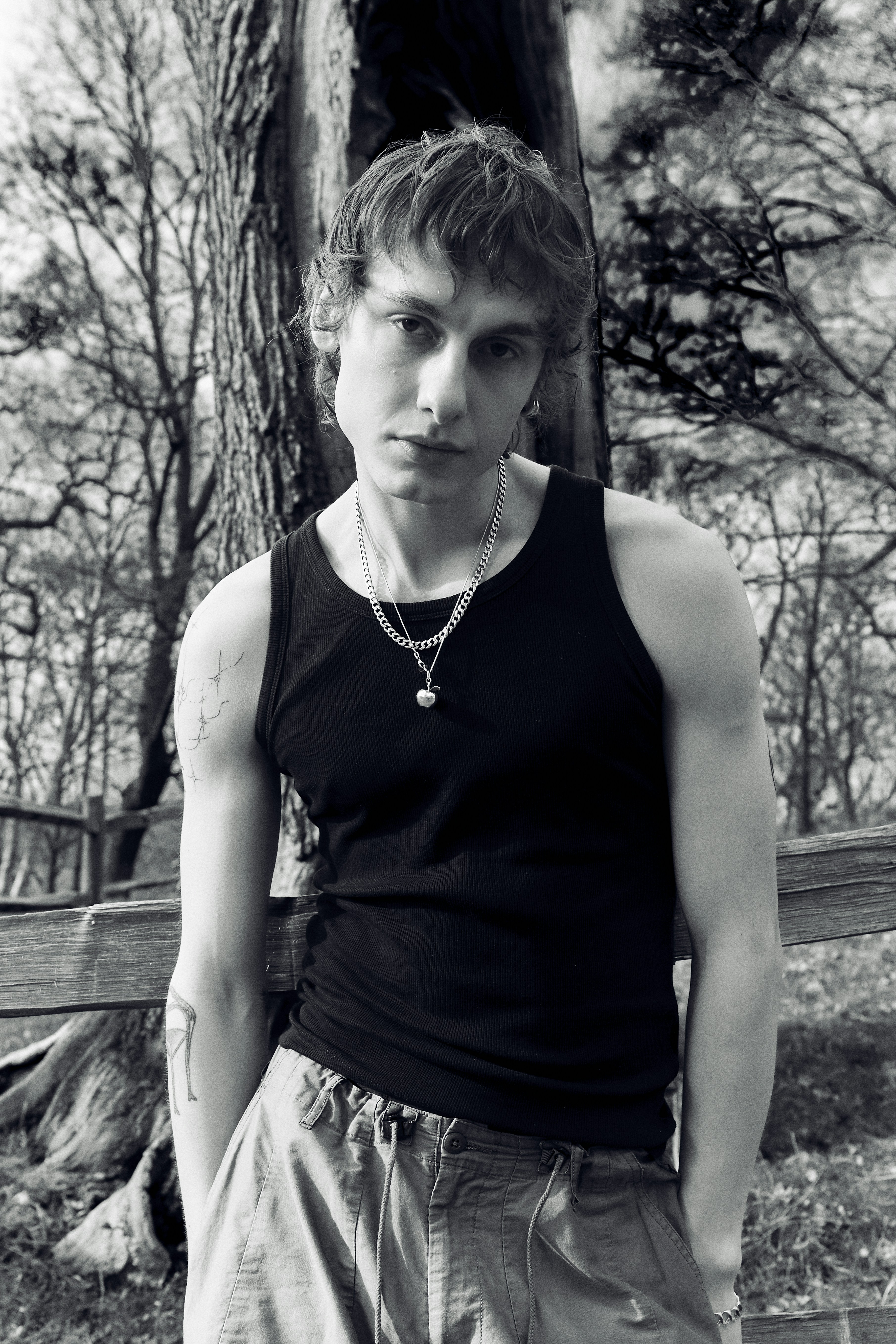 a young man standing in front of a tree