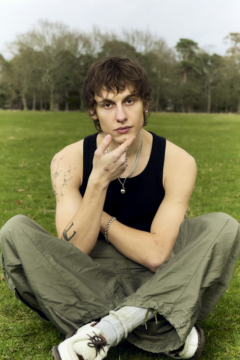 a man sitting in the grass with his hand on his chin