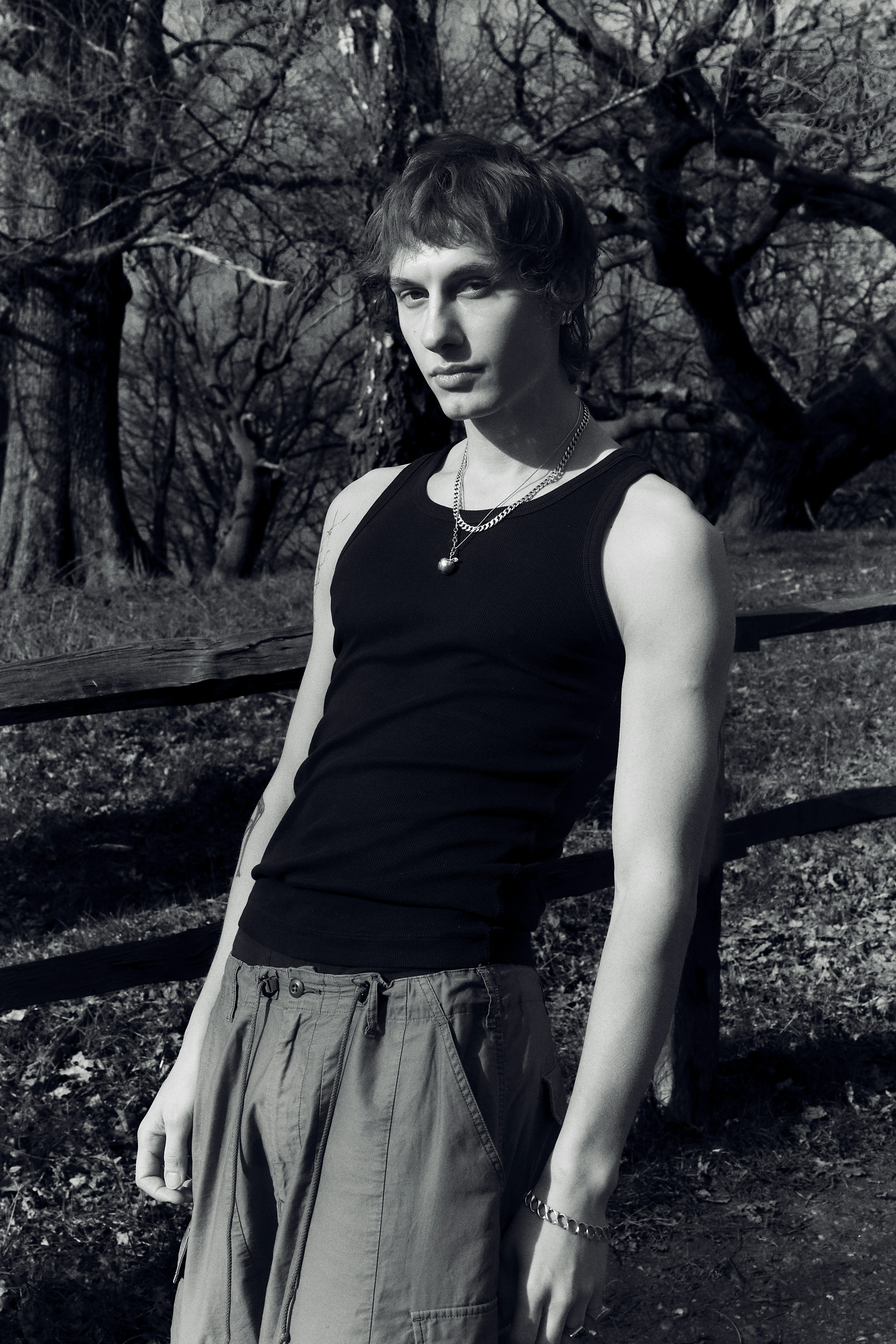 a young man standing in front of a wooden fence