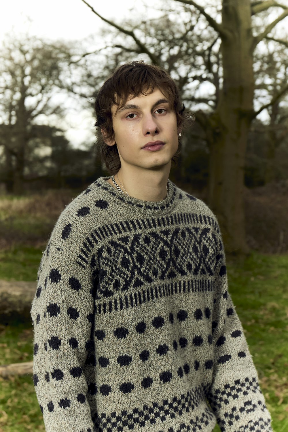 a young man standing in front of a tree