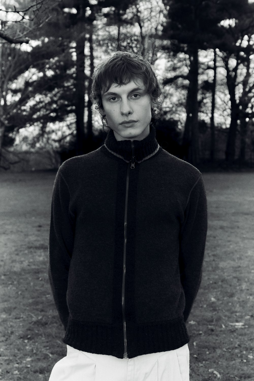 a man standing in a field with trees in the background