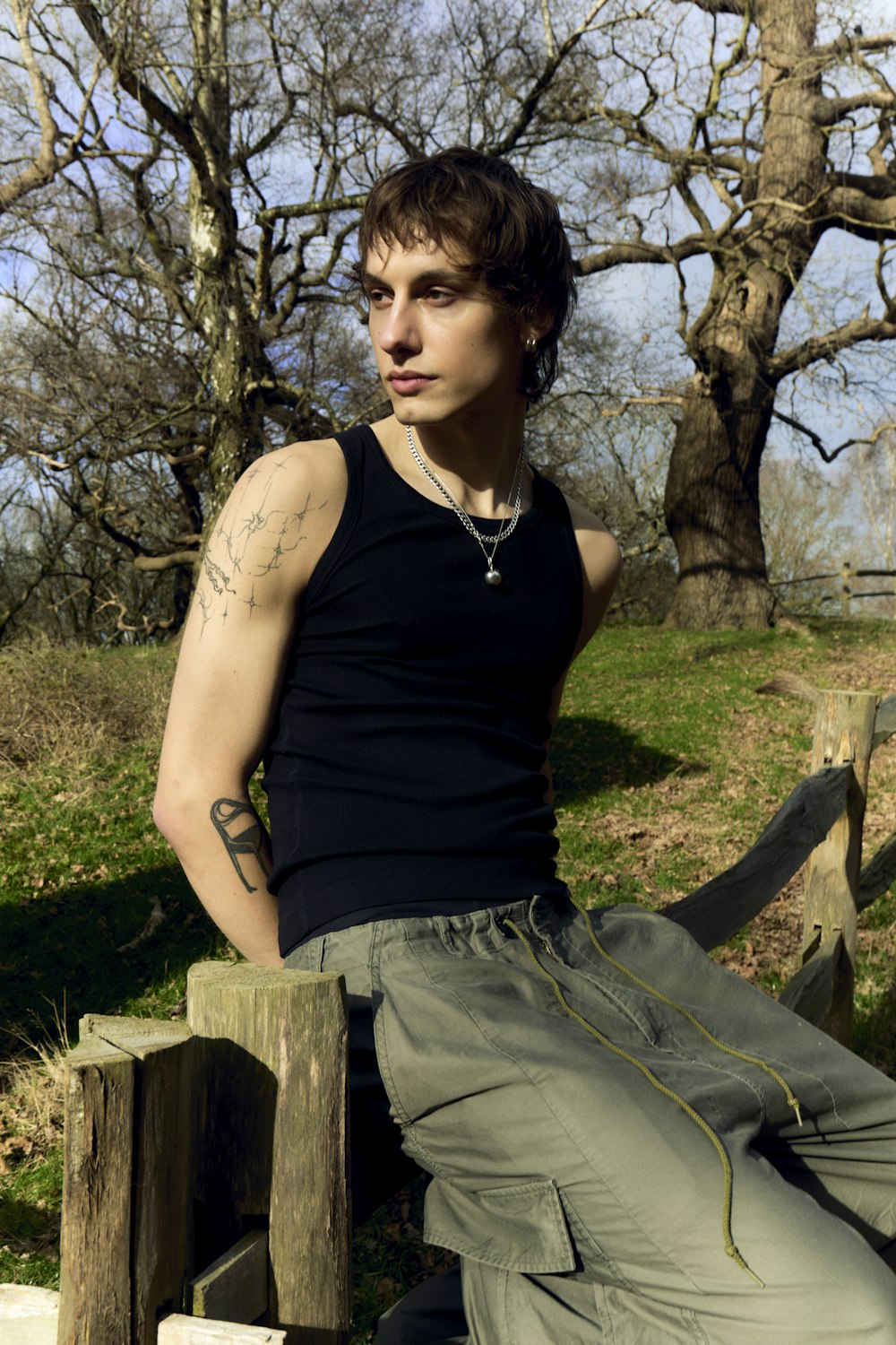 a man with tattoos sitting on a wooden bench