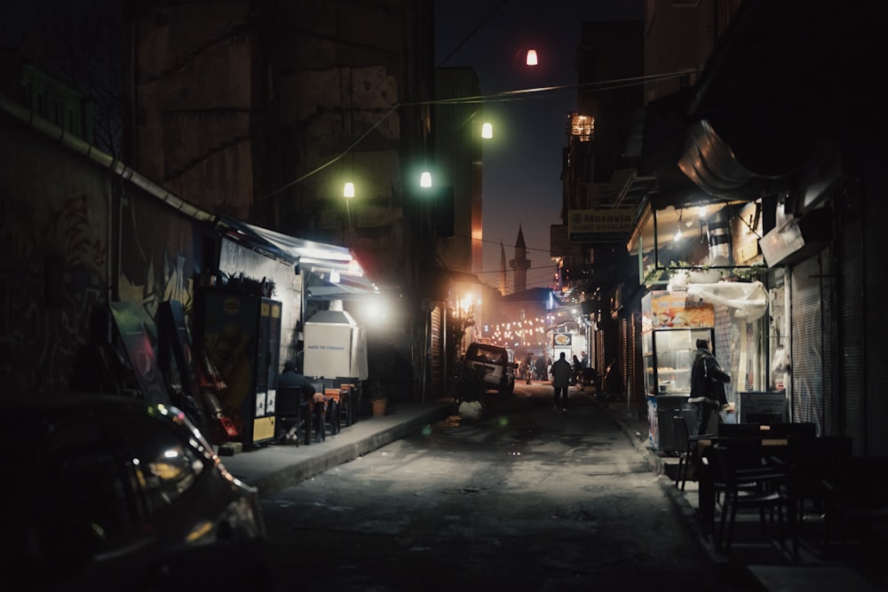 a city street at night with cars parked on the side of the street