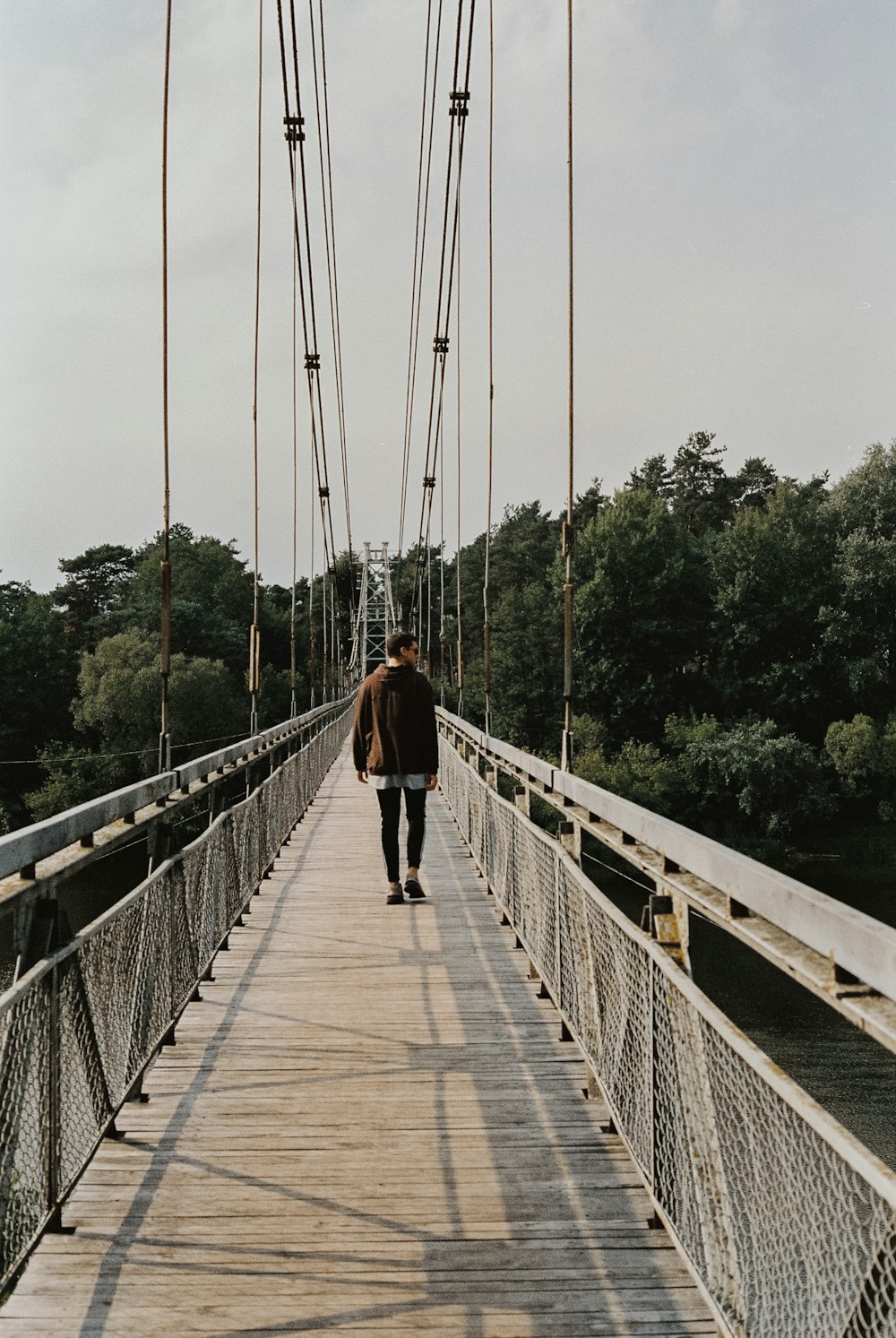 ein Mann, der über eine Brücke über einen Fluss geht