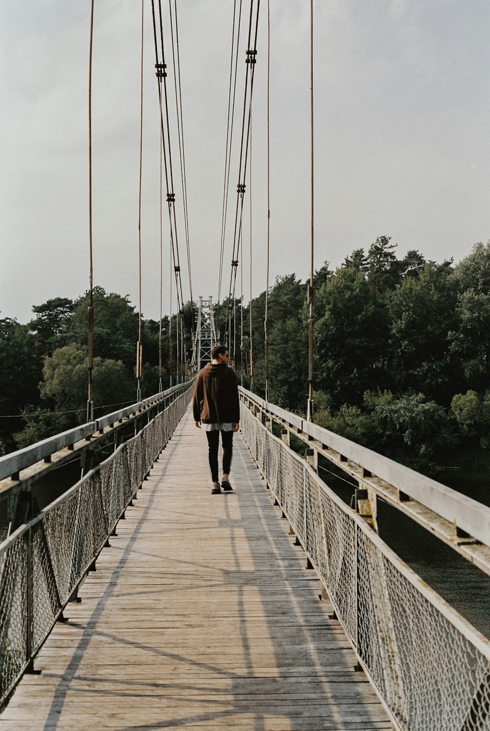 a man walking across a bridge over a river