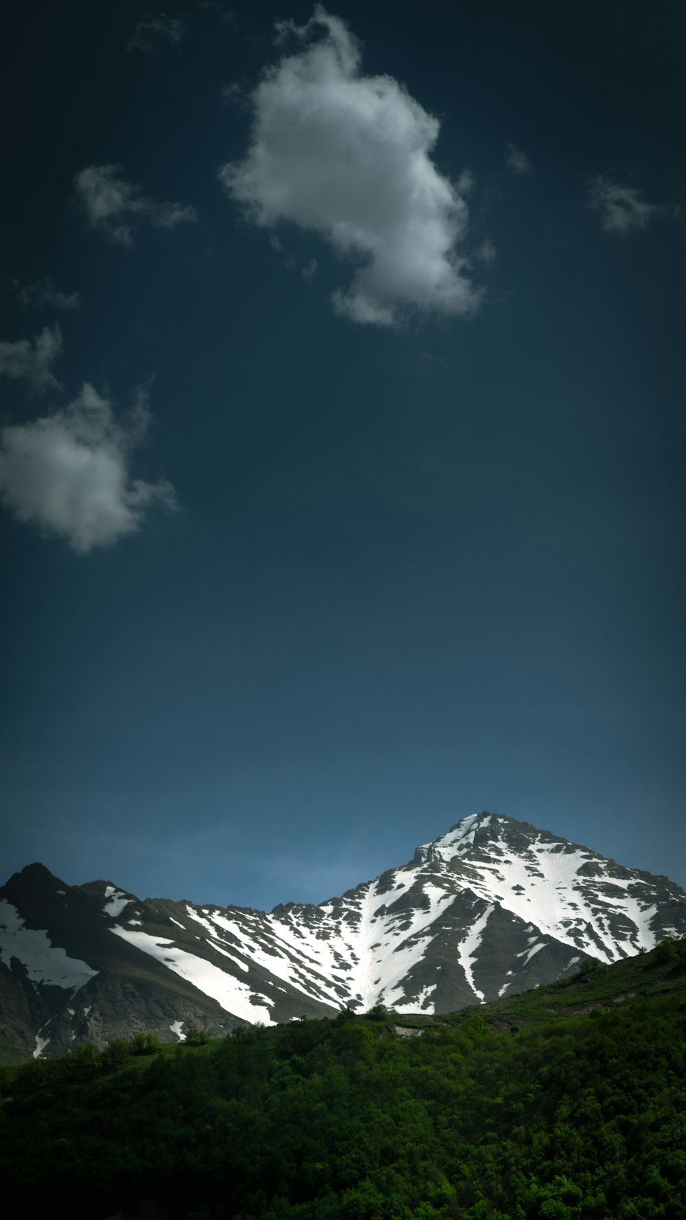 a snow covered mountain under a cloudy blue sky