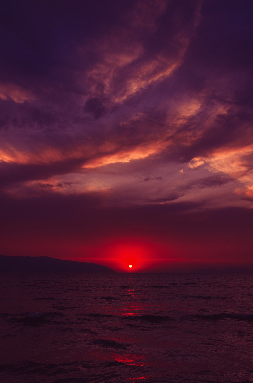 Il sole sta tramontando sull'oceano in una giornata nuvolosa