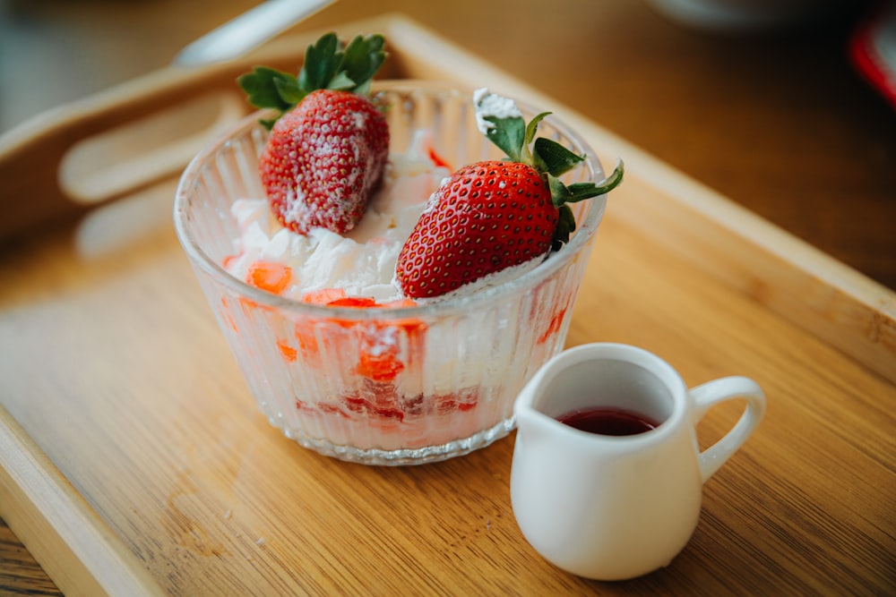 a bowl of strawberries and a cup of tea on a tray