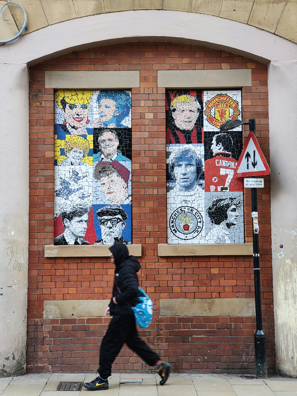 a person walking past a brick building with posters on it