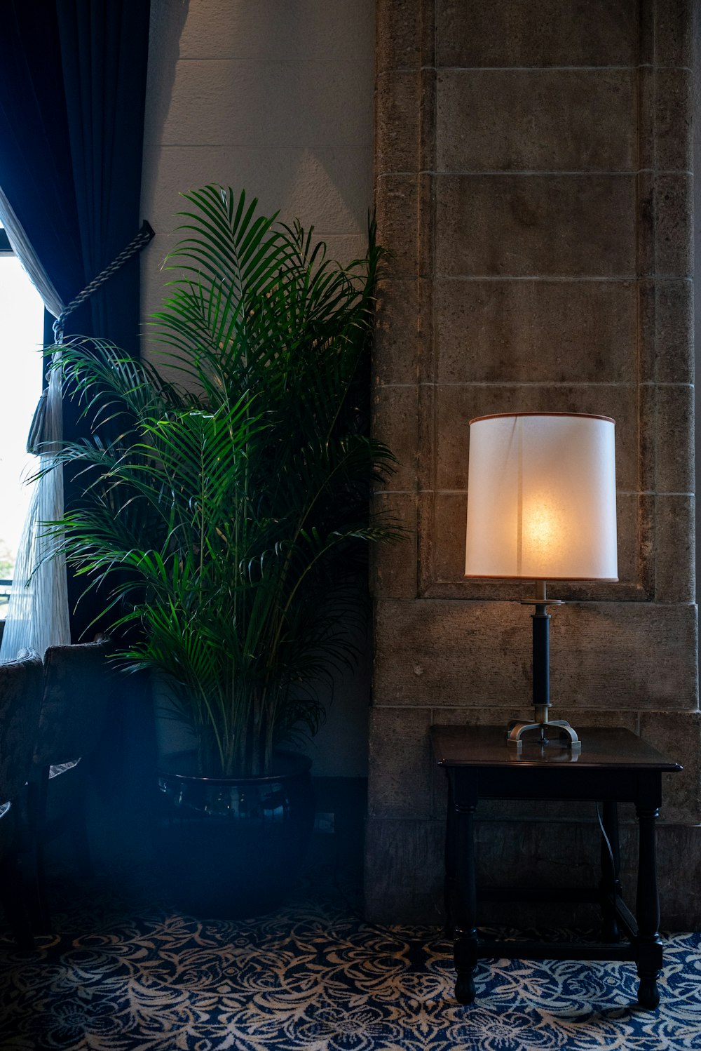 una lámpara que está sobre una mesa junto a una planta en maceta