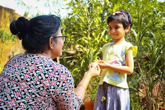 a woman holding a little girl's hand in a garden