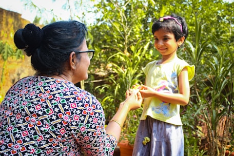 a woman holding a little girl's hand in a garden