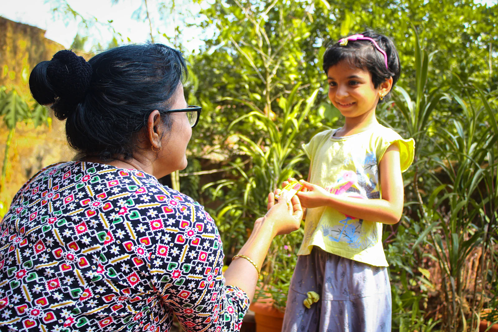 An Indian mother holding her daughter's hand in a garden