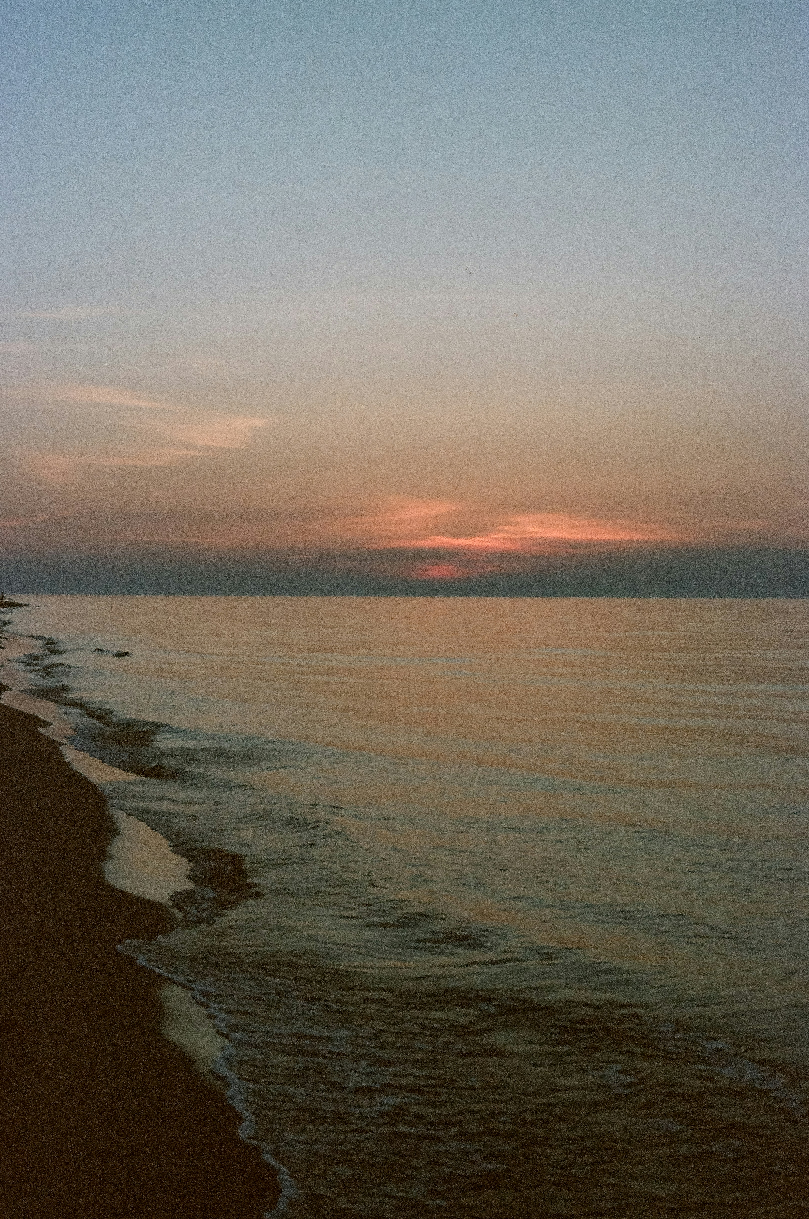 the sun is setting over the water at the beach