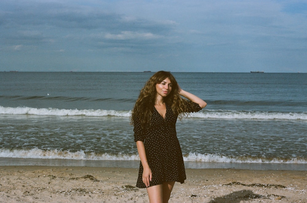 a woman standing on a beach next to the ocean