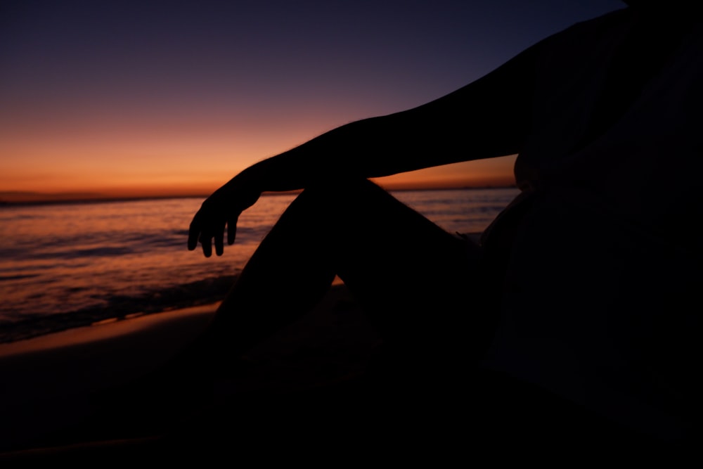 a person sitting on a beach at sunset