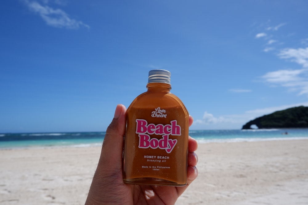 a person holding a bottle of beach body on a beach