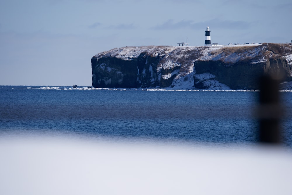 a lighthouse on a rocky outcropping in the middle of the ocean