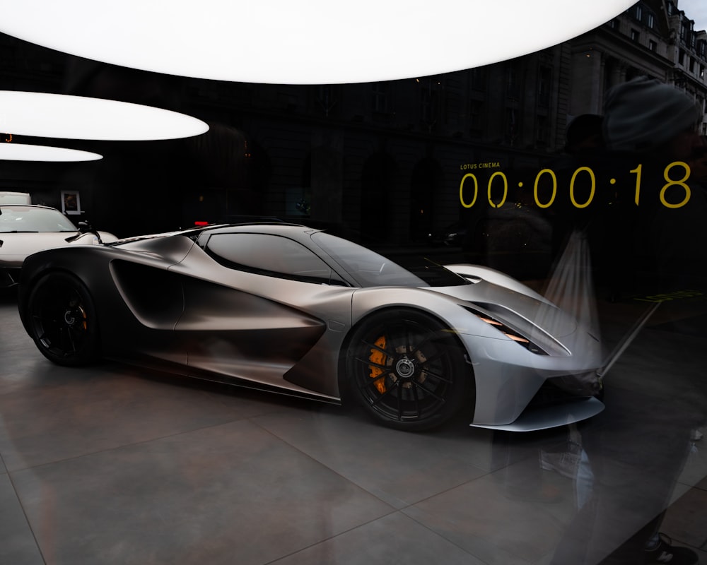 a silver sports car parked in front of a clock